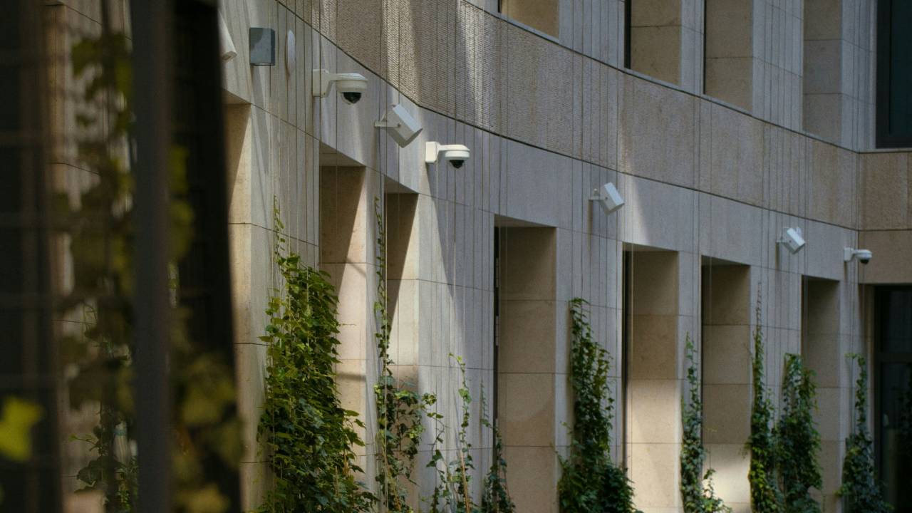 A dozen CCTV cameras mounted on the wall of a building