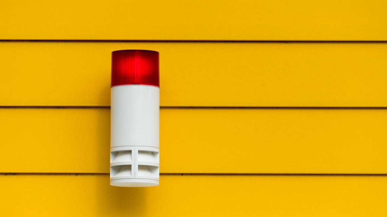 An alarm system installed on a yellow wall.