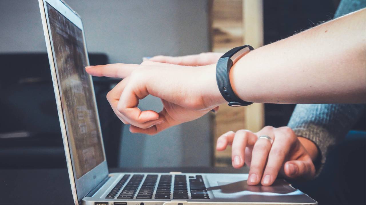 A person pointing at something on a laptop screen